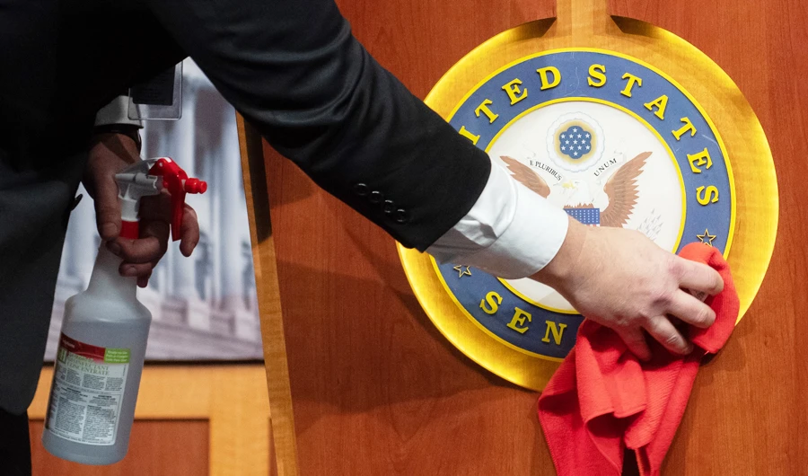 Mike Mastrian, director of the Senate Radio and TV Gallery, disinfects the podium prior to a press briefing with US Senate Majority Leader Mitch McConnell, Republican of Kentucky about the response to COVID-19, known as coronavirus, at the US Capitol in Washington, DC, March 17, 2020. (AFP)
