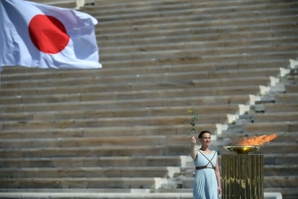A perfomer stands next to the Olympic flame during the olympic flame handover ceremony for the 2020 Tokyo Summer Olympics, on March 19, 2020 in Athens. (AFP)
