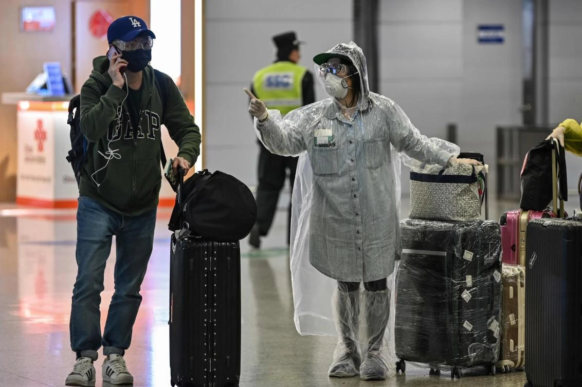 Passengers wearing face masks, amid concerns of the COVID-19 coronavirus, arrive at Shanghai Pudong International Airport in Shanghai in March 19, 2020. ( AFP)