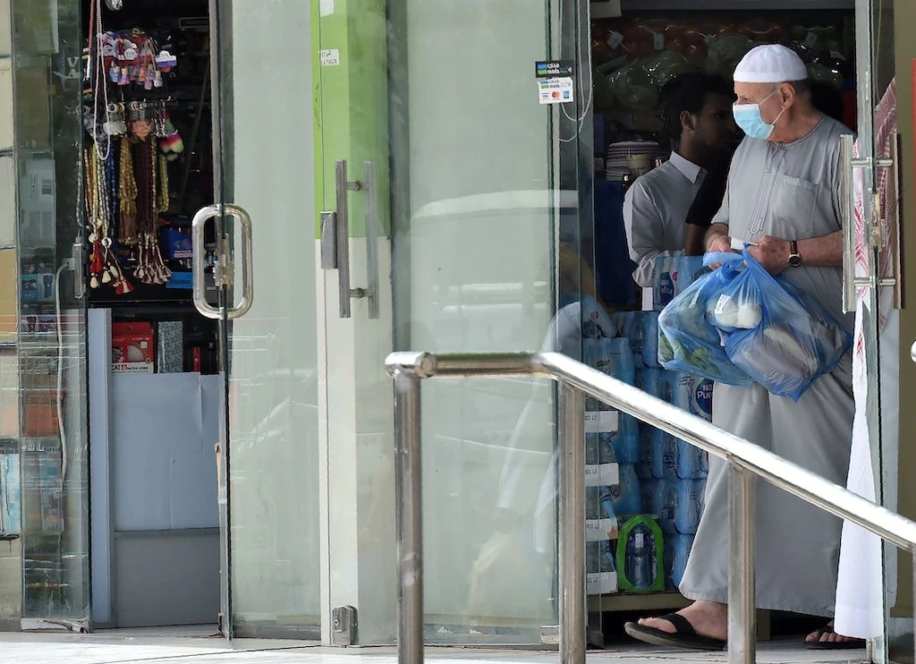 A man wearing a protective mask , precaution against COVID-19 coronavirus disease, exits a supermarket with merchandise in the centre of the Saudi capital Riyadh on March 15, 2020. (AFP)