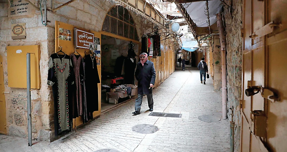 People walk in the deserted old city of Hebron in the Israeli occupied West Bank amidst the COVID-19 pandemic. The Palestinian Authority has imposed curfews in Bethlehem and other West Bank cities. (AFP)