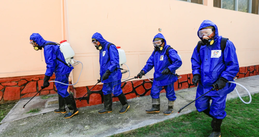 Health workers wearing protective suits spray disinfectant outside of a building during an awareness campaign for COVID-19 in Jalalabad on Thursday. (Reuters)