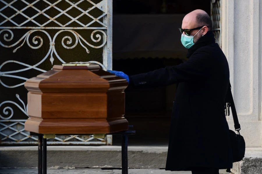 A man touches the coffin of his mother during a funeral service in the closed cemetery of Seriate, near Bergamo, Lombardy, on March 20, 2020 during the country's lockdown aimed at stopping the spread of the COVID-19 (new coronavirus) pandemic. (AFP/Piero Cruciatti)