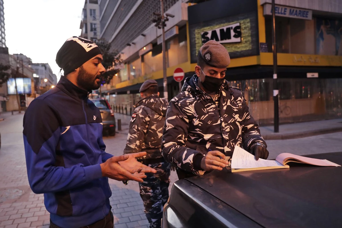 A Lebanese policeman fines a man for violating lockdown rules in Beirut's Hamra street on March 21, 2020. (AFP)