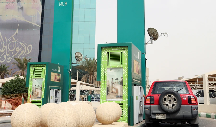 A man in a car withdraws money from an ATM outside the Saudi National Commercial Bank (NCB), after an outbreak of coronavirus, in Riyadh, Saudi Arabia, March 18, 2020. (REUTERS)