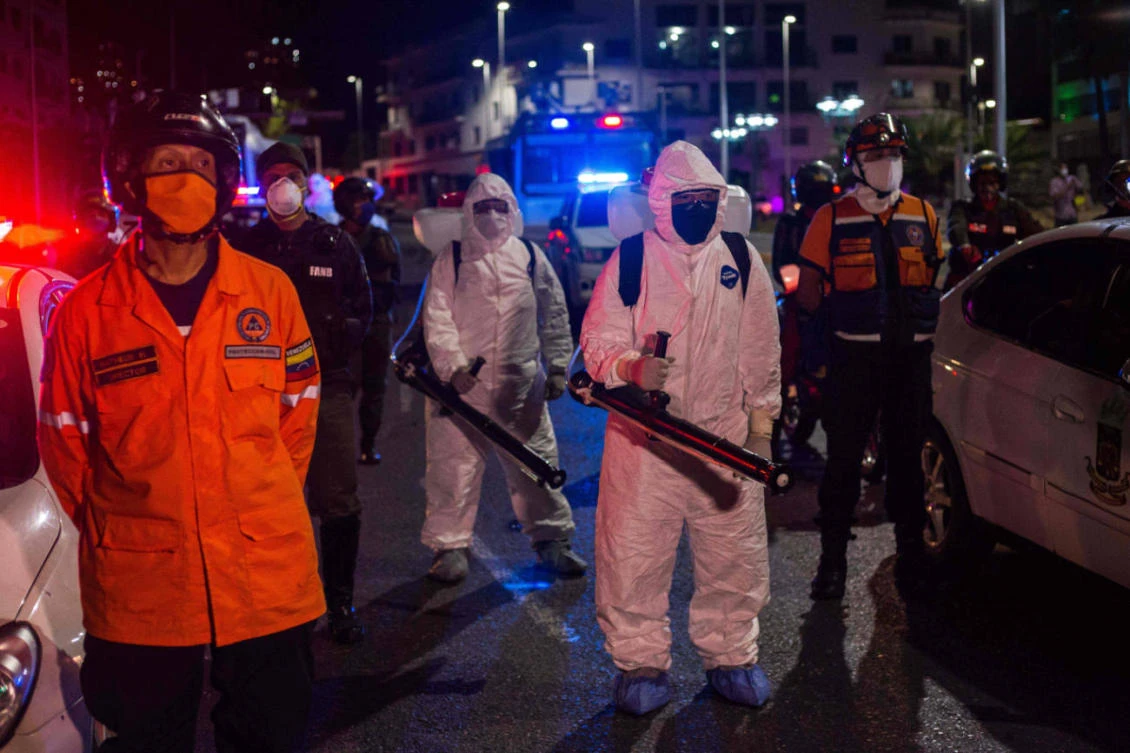 Municipal workers wearing protective gear take part in a cleaning campaign as a preventive measure against the spread of the new coronavirus COVID-19, in Caracas, on March 21, 2020. (AFP / Cristian Hernandez)