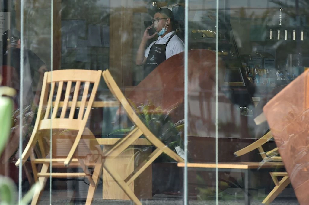 A picture taken March 18, 2020 shows a waiter speaking on his mobile phone inside a closed cafe in Riyadh amid measures to contain the novel COVID-19 coronavirus disease in the desert kingdom. (AFP)