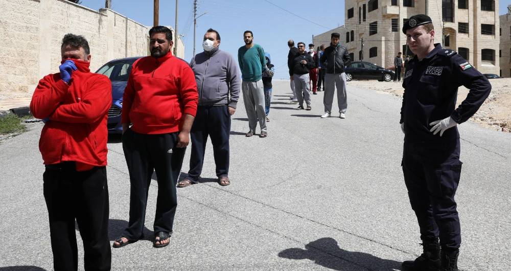 People stand in line to buy bread from a bus in front of their homes after Jordan announced it would extend a curfew indefinitely. (Reuters)