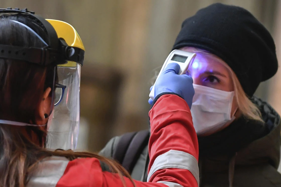 A Red Cross employee checks the temperature of a traveller at the access gate for departures in deserted central station in Milan, Italy, Wednesday, March 25, 2020. (AP)