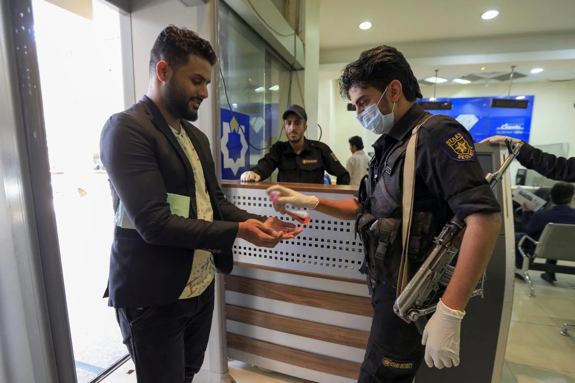A security guard sprays hand sanitiser on customer's hands at the entrance of a bank in the Yemeni capital Sanaa on March 24, 2020 amid the COVID-19 coronavirus pandemic. (AFP)