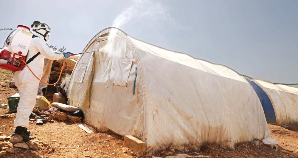 Syrian Civil Defense, also known as the White Helmets, disinfects a tent for the displaced in Idlib as part of efforts to prevent the spread of coronavirus. (AFP)