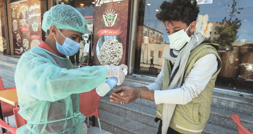 A restaurant worker sprays a sanitizer on a customer’s hand in Sanaa on Wednesday. (AFP)
