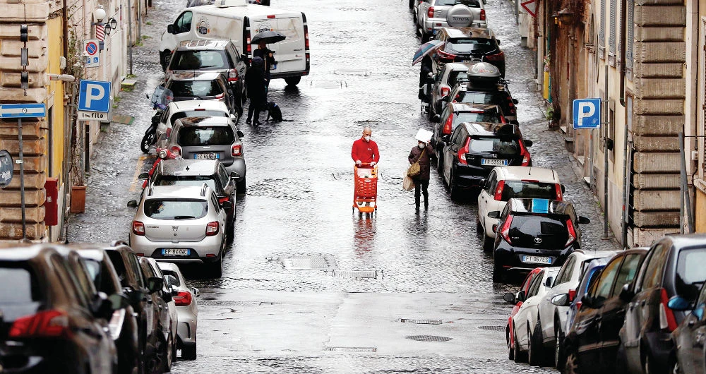 A man wearing a protective mask pushes a shopping cart in an almost empty street during the virus outbreak in Rome Thursday. (Reuters)
