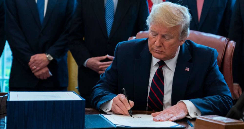 Trump signs the bill. (AP)