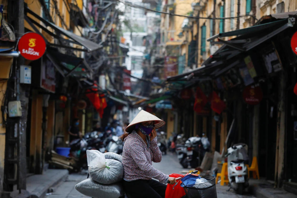 A woman wears a protective mask as she rides past an empty street during the coronavirus disease (COVID-19) outbreak in Hanoi, Vietnam March 26, 2020. (Reuters)