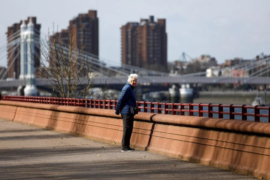 An elderly woman looks out over the River Thames as she walks to get her exercise in Battersea Park in London on March 28, 2020, as life continues in Britain during the novel coronavirus pandemic. (AFP)