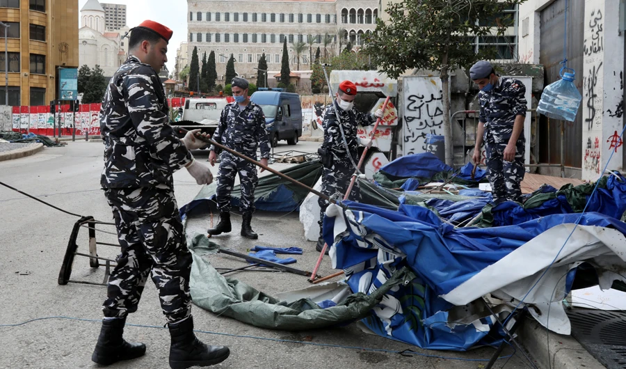 Lebanese forces pull down tents as they clear away a protest camp in Beirut on Saturday as part of efforts to curb the spread of the coronavirus disease (COVID-19). (Reuters)