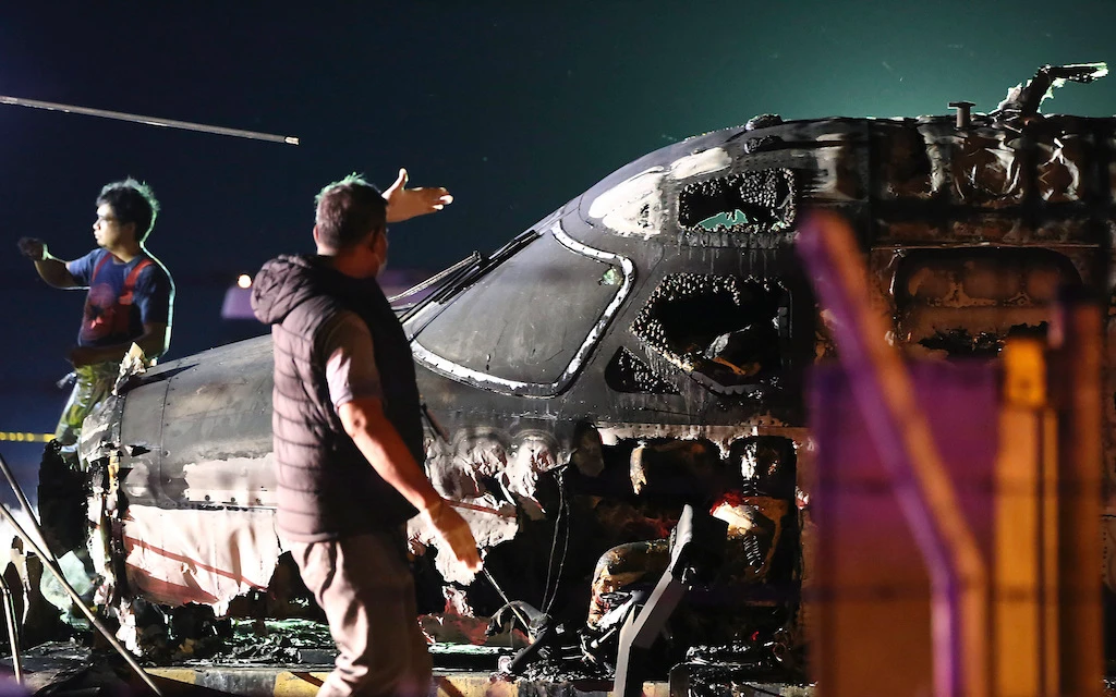 An airport personnel walks beside the remains of a Lion Air, West Wind 24 aircraft after it caught fire during take off at Manila's International Airport in Philippines on Sunday, March 29, 2020. (AP)