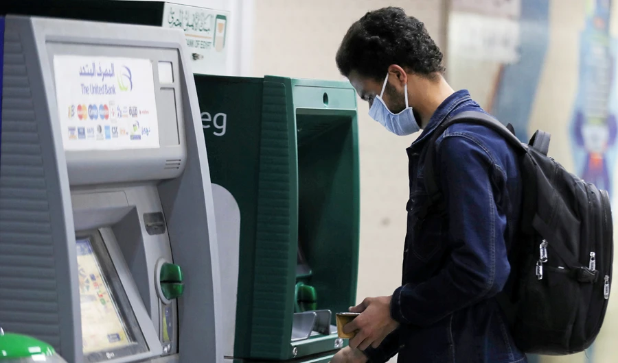 A man wearing a protective face mask withdraws money from an ATM at the Al Shohadaa "Martyrs" metro station as Egypt ramps up efforts to slow the spread of coronavirus disease COVID-19 in Cairo, Egypt, March 22, 2020. (REUTERS)