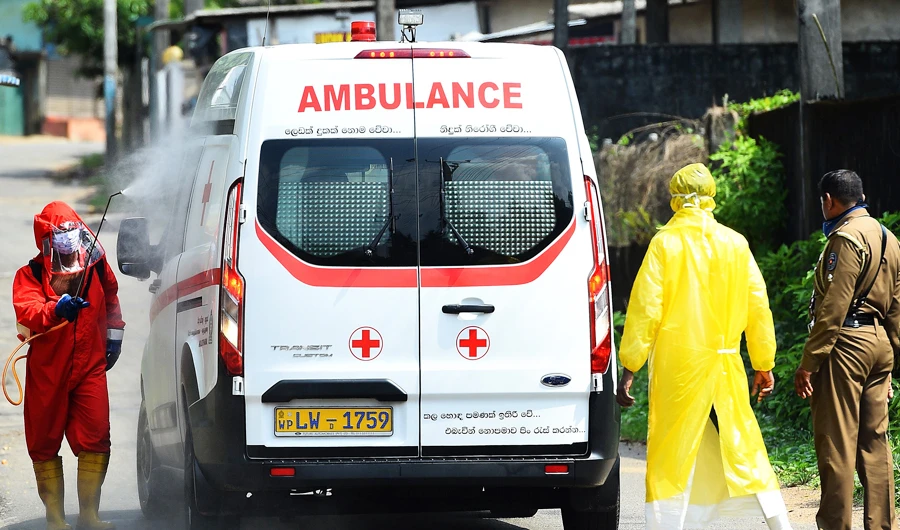 A municipal worker sprays disinfectant on an ambulance in Atulugama on March 29, 2020, after the town was sealed off by health authorities following fears that it could be a cluster for COVID-19 infection after two positive cases. (AFP)