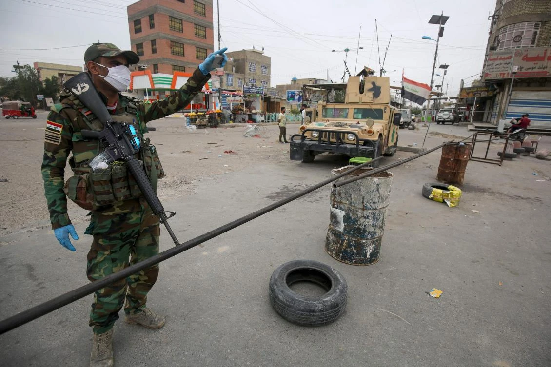 Iraqi soldiers, wearing protective face-masks and gloves, man a checkpoint at Sadr City on March 28, 2020 as the country ties to stem the spread of the COVID-19. (AFP)