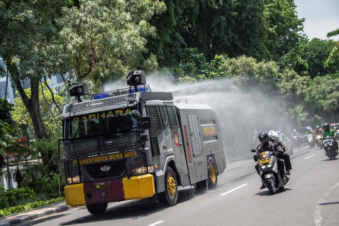An Indonesian police riot control vehicle sprays disinfectant amid the COVID-19 coronavirus outbreak in Surabaya. (AFP)