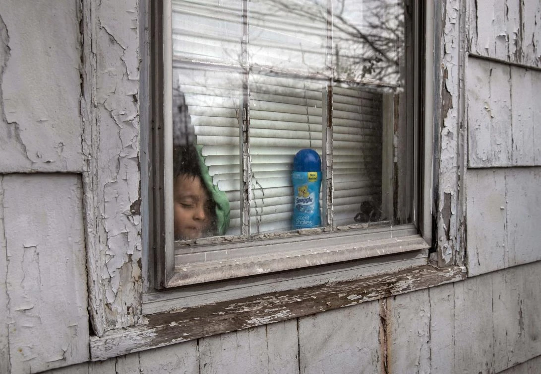 An undocumented Honduran immigrant, 4, sick and isolated with his family for the last two weeks, stands inside his bedroom window on March 30, 2020. (John Moore/Getty Images/AFP)
