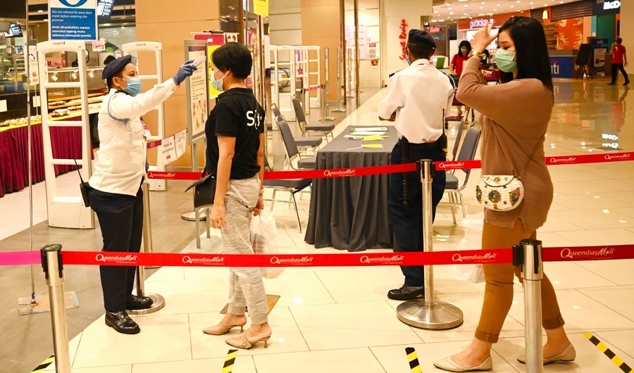 A security guard checks the temperatures of customers arriving at a supermarket during the partial lockdown in Malaysia to contain the spread of the COVID-19 coronavirus in Penang on March 27, 2020. (AFP)