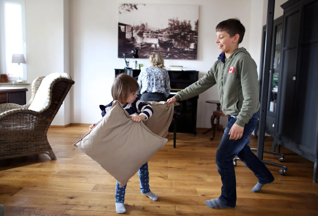 German sopranist and member of the ensemble of Leipzig's opera house (Oper Leipzig), Lilli Wuenscher sings as her ten-year-old son Joshua and three-year-old daughter Josephine have a pillow fight at their home, where the family stays stays confined due to the pandemic of the novel coronavirus, on April 3, 2020 on the outskirts of Leipzig, eastern Germany. The gates of the Leipzig Opera have been closed for about three weeks due to the novel corona pandemic - but the voices and instruments of the artists are far from silent. / AFP / Ronny Hartmann