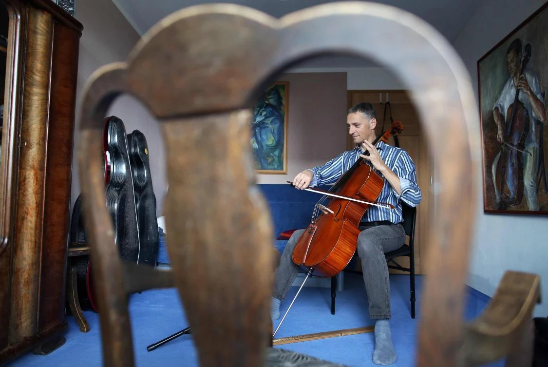 German musician Stephan Wuensch, principal cellist of Leipzig's opera house (Oper Leipzig), plays the violoncello at home, where he stays confined with his family due to the pandemic of the novel coronavirus, on April 3, 2020 on the outskirts of Leipzig, eastern Germany. The gates of the Leipzig Opera have been closed for about three weeks due to the novel corona pandemic - but the voices and instruments of the artists are far from silent. / AFP / Ronny Hartmann