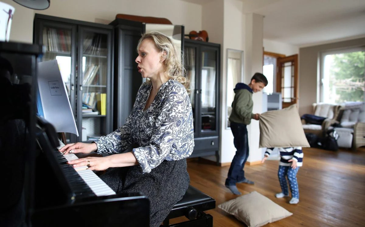 German sopranist and member of the ensemble of Leipzig's opera house (Oper Leipzig), Lilli Wuenscher sings as her ten-year-old son Joshua and three-year-old daughter Josephine have a pillow fight at their home, where the family stays confined due to the pandemic of the novel coronavirus, on April 3, 2020 on the outskirts of Leipzig, eastern Germany. The gates of the Leipzig Opera have been closed for about three weeks due to the novel corona pandemic - but the voices and instruments of the artists are far from silent. / AFP / Ronny Hartmann