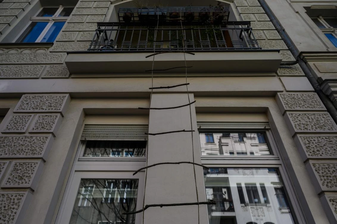 An art installation featuring a rope ladder made of wooden sticks, part of the "Balconies, Life, Art, Pandemic, and Proximity" exhibition, is seen in Berlin on April 12, 2020, amid a new coronavirus COVID-19 pandemic. Over 30 artists are taking part in the two-day exhibition which calls on "the artistic community living in [Berlin's district of] Prenzlauer Berg to activate / exhibit / inhabit / their windows and balconies on Easter Sunday and Monday". Curated by Ovul Durmusoglu and Joanna Warsza, the exhibition boasts "zero budget, no openings, no crowds, just a proposition of a stroll that would connect dots in solidarity and togetherness". / AFP / John MACDOUGALL