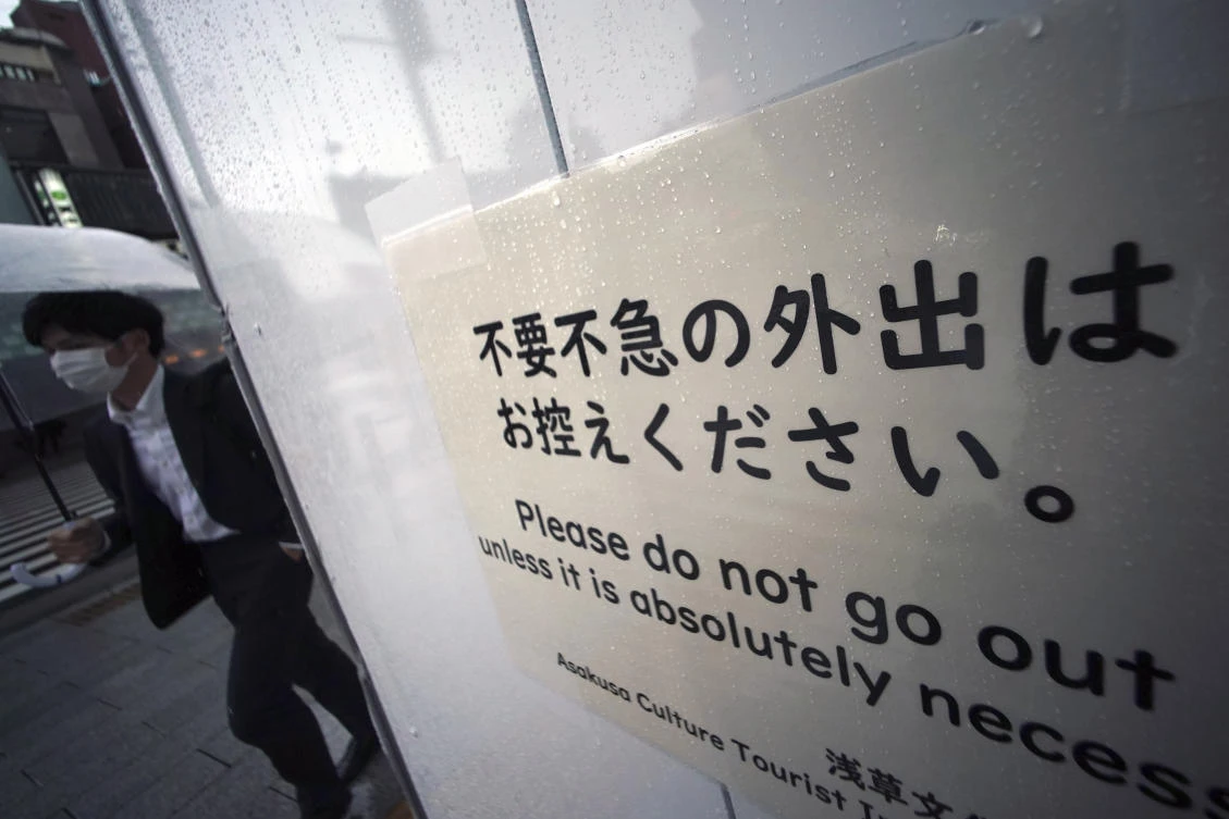 A man walks near a sight saying ‘Please do not go out unless it is absolutely necessary’ in the empty Asakusa district on Wednesday, April 1, 2020, in Tokyo. (AP)