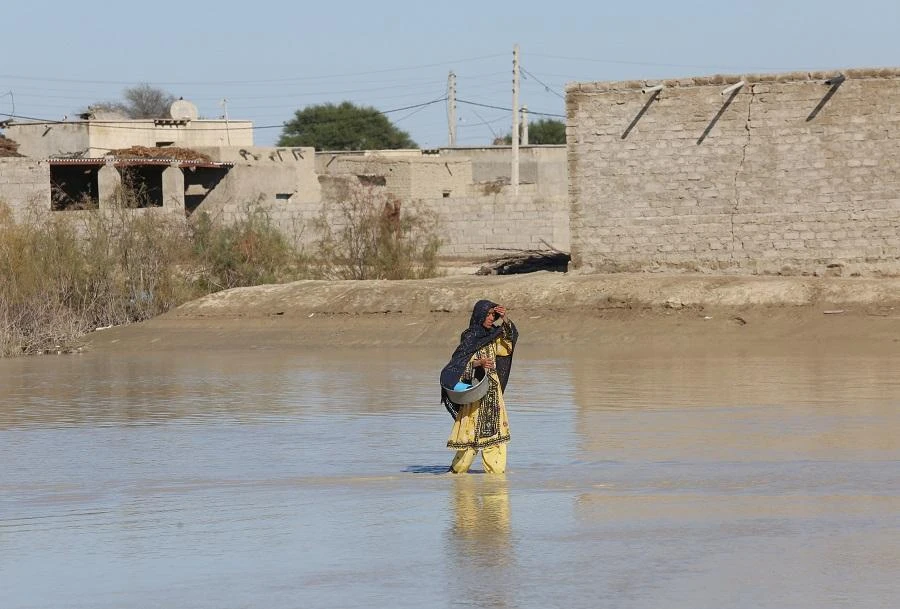 An Iranian woman walks through a flooded road on January 13, 2020 in the village of Dashtiari in Iran's Sistan-Baluchistan region, as severe downpour led to floods across region, blocking roads and damaging homes. (File/AFP)