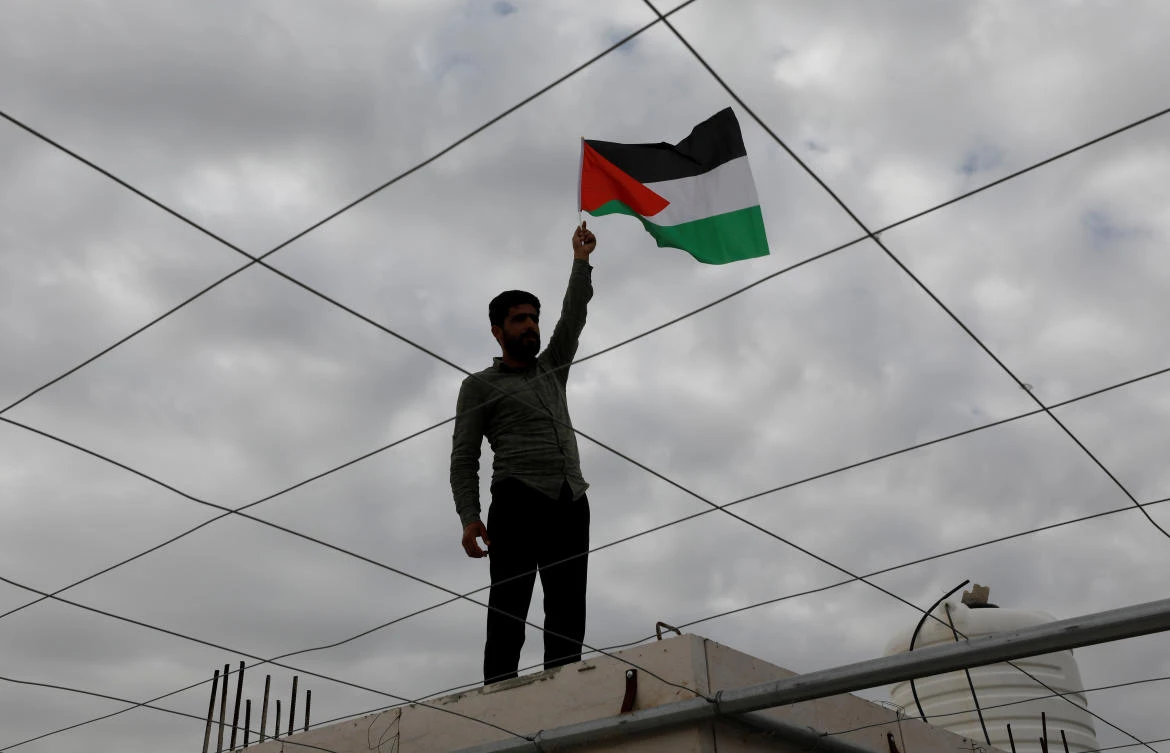 A man holds a Palestinian flag on his home rooftops to mark Land Day as mass rallies planned to commemorate the event were cancelled amid concerns about the spread of coronavirus disease (COVID-19), near Hebron in the Israeli-occupied West Bank March 30, 2020. (Reuters)