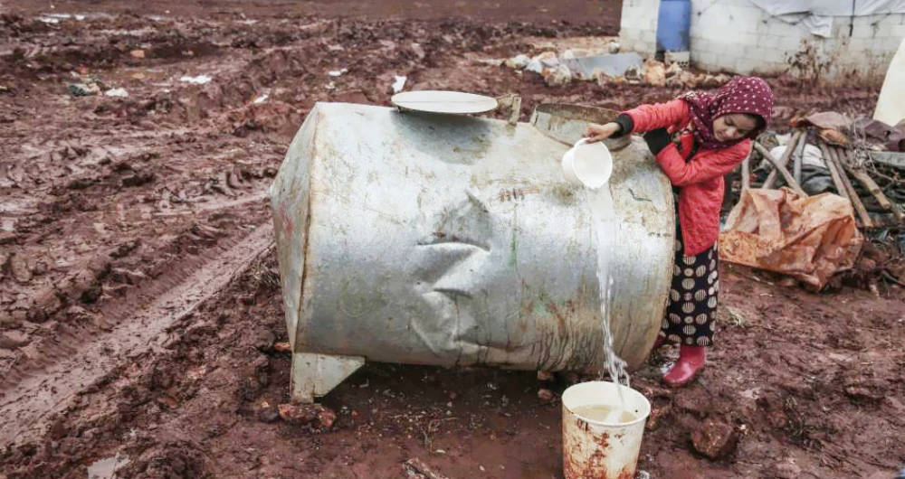 A displaced Syrian girl fills water from a cistern at a refugee camp in the northern countryside of Idlib. (AP)