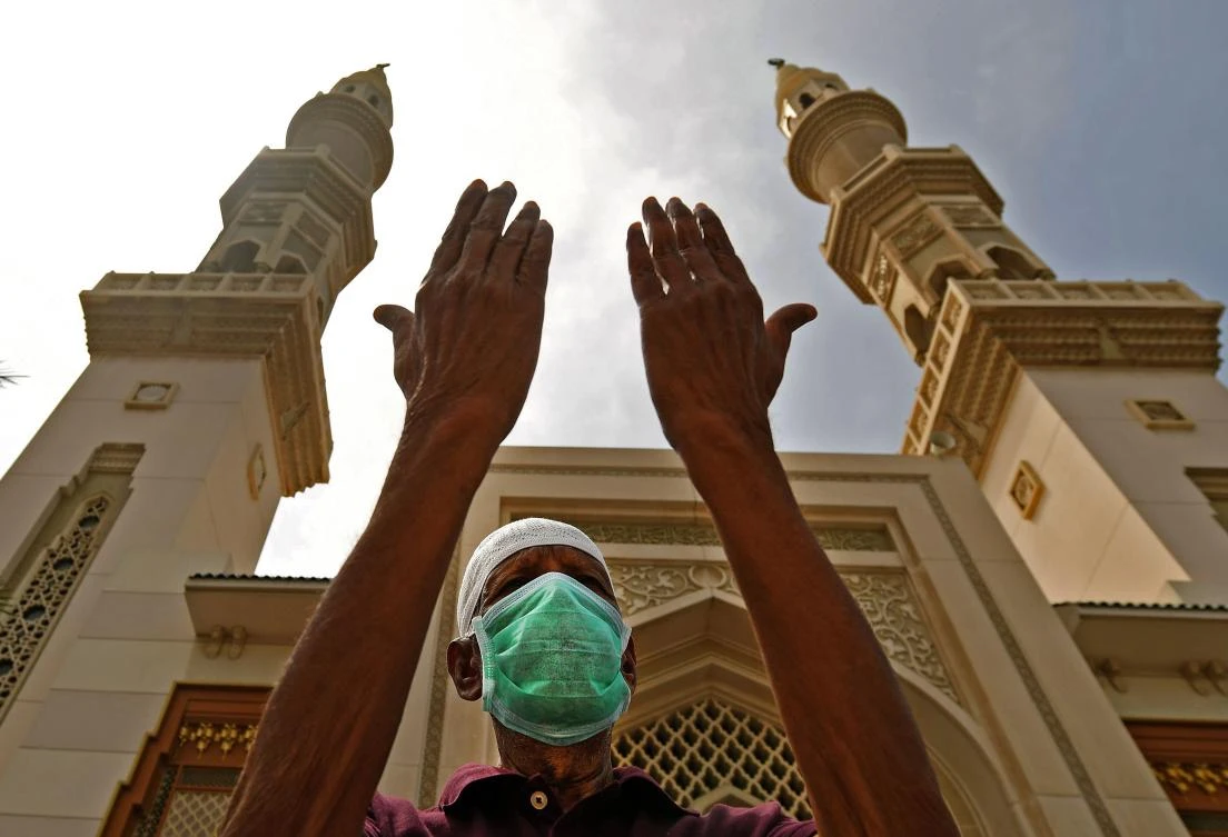 A man wearing a protective mask lifts his hands in prayer outside a mosque which has been closed to worshipers amid the COVID-19 pandemic, in Sharjah, in the UAE, March 30, 2020. (AFP)