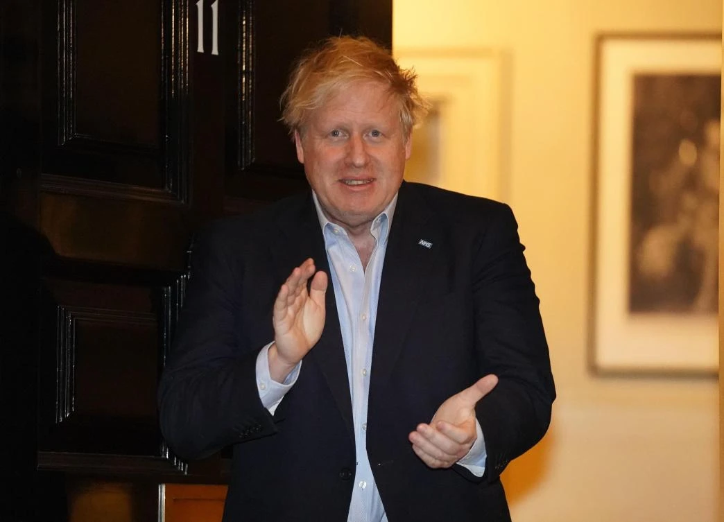 A handout image released by 10 Downing Street, shows Britain's Prime Minister Boris Johnson as he participates in a national "clap for carers" to show thanks for the work of Britain's National Health Service (NHS) workers and frontline medical staff around the country as they battle with the novel coronavirus pandemic, in the doorway of 10 Downing Street in central London on April 2, 2020. (AFP)