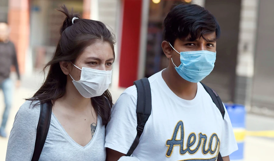 A couple wear face masks as they walk along Madero street in Mexico City on April 1, 2020. (AFP)