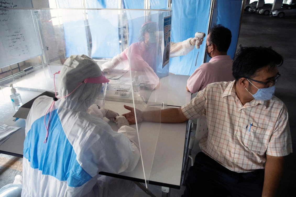 Medical workers wearing protective suits measures the body temperature of a man and another draws blood for the preliminary blood test of tested for COVID-19 at the Chulalongkorn University Health Service Center in Bangkok, Thailand, April 2, 2020. (Reuters)