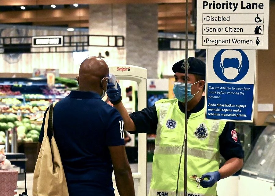 A policeman checks the temperature of a shopper entering a supermarket as Malaysia implements Movement Control Order as tighter restrictions to combat the spread of the COVID-19 novel corinavirus in Penang on April 3, 2020. (File/AFP)