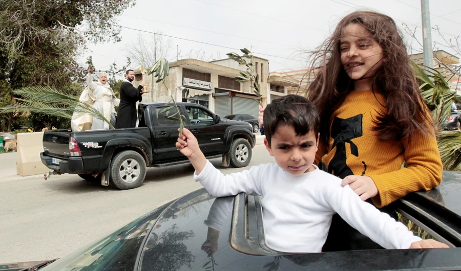 Children hold olive branches as they look out from the sunroof of a car to be blessed by priests roaming around neighborhoods to celebrate Palm Sunday in Lebanon. (Reuters)