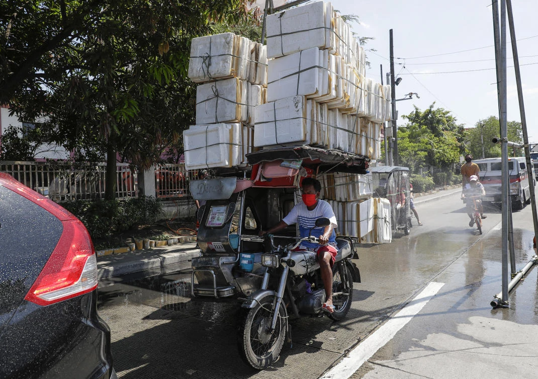 A man on a pedicab drives past a spray of disinfectants during an enhanced community quarantine in Manila, Philippines on Friday, April 3, 2020. (AP)