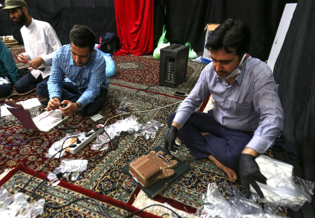 Above, residents make protective gloves inside a mosque in Tehran. Iran is the most coronavirus-affected country in the Middle East. (AFP)