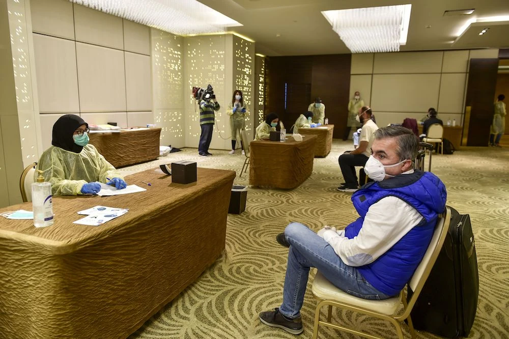 Medical personnel speak to a Lebanese national, residing in Saudi Arabia, in the lobby of a hotel, where they will be housed, in the capital Beirut. (AFP)