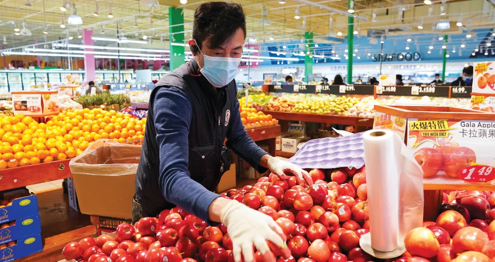 A worker restocks apples at an Asian grocery store in Virginia amid hopes that the rate of new coronavirus infections may hit its peak in the US. (Reuters)