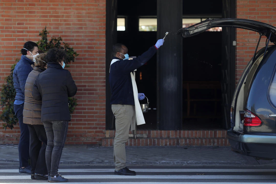 The pace of coronavirus deaths in Spain ticked up slightly for the first time in five days on Tuesday. Above, a priest blesses a coffin during a burial in Madrid. (AP)