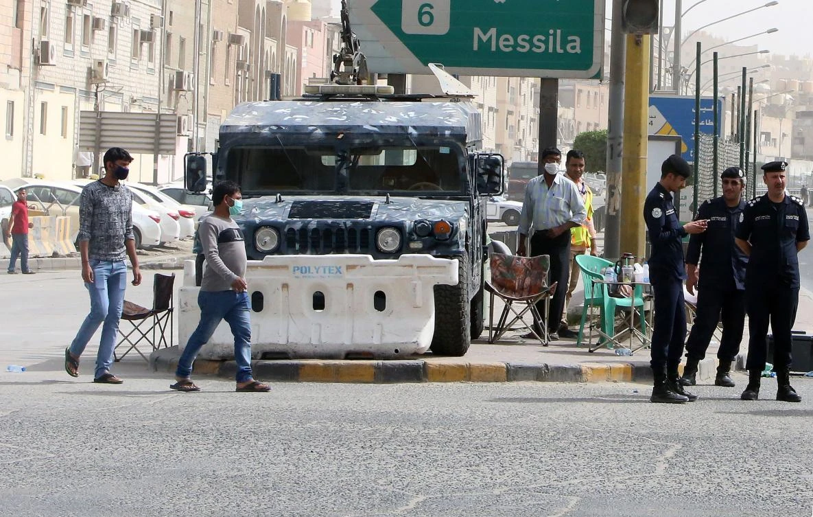 Kuwaiti police officers man a checkpoint at Jleeb Al-Shuyoukh, above, on two heavily populated areas where poorer expatriate workers live. (AFP)
