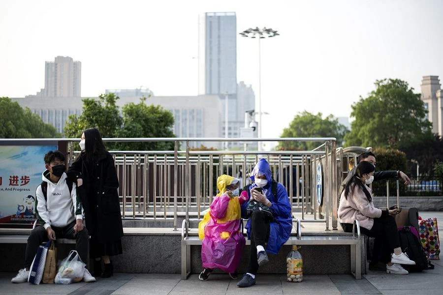 People wearing face masks sit outside Hankou Railway Station in Wuhan as people arrive in the hope of taking one of the first trains leaving the city in China's central Hubei province early on April 8, 2020. (File/AFP)