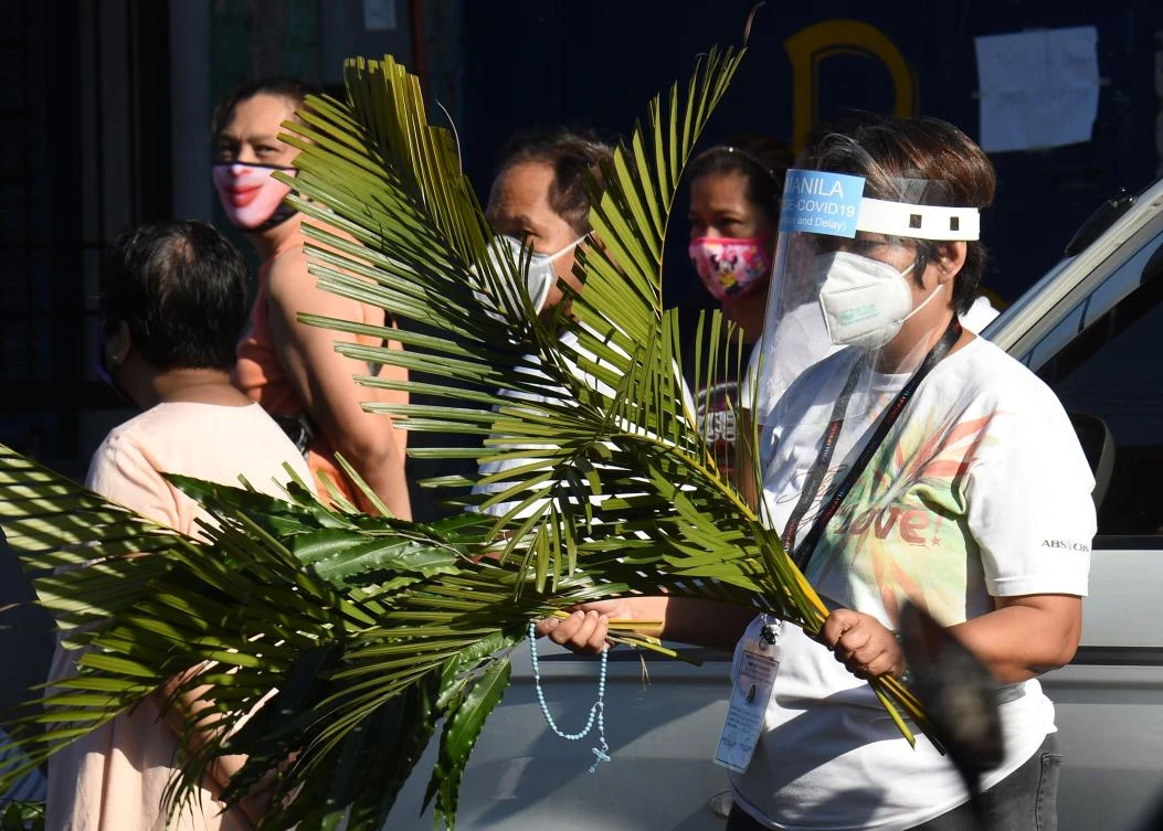 Residents wait for a priest for the blessing during the Palm Sunday event in Manila on April 5, 2020, as part of the Easter observance. (AFP)